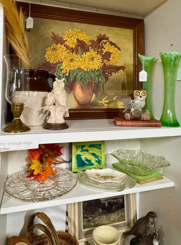 Framed still life of golden mums with tall green glass vases and a white owl figurine