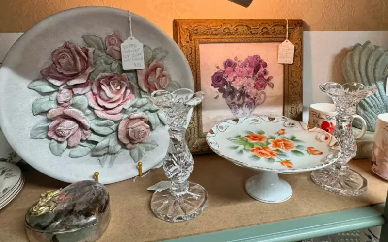 Plate with sculpted pink roses beside crystal candlesticks and a painted cake stand