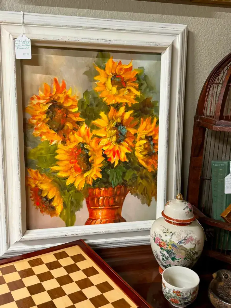 Painting of sunflowers in a copper vase in a whitewashed frame