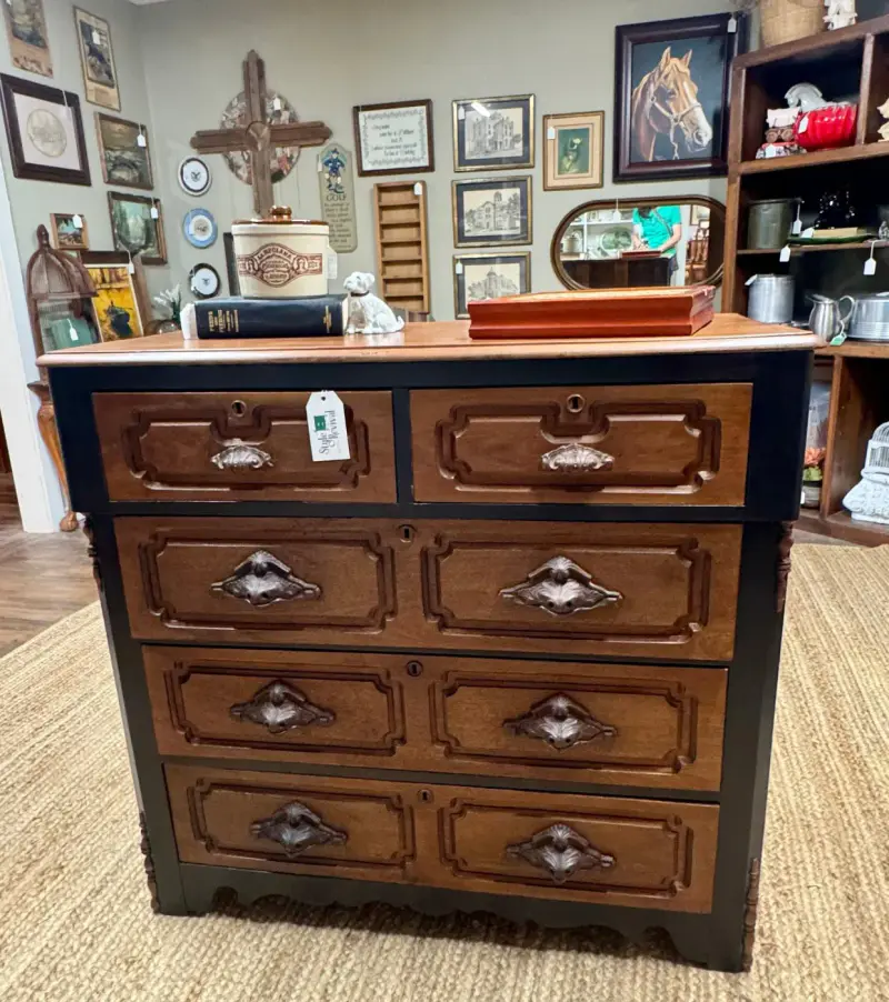 Chest of drawers with carved leaf pulls on warm wood drawers and black sides