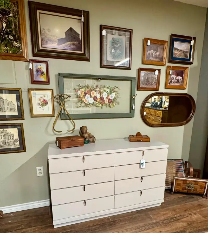 White eight-drawer dresser under a gallery wall of framed art and a floral print